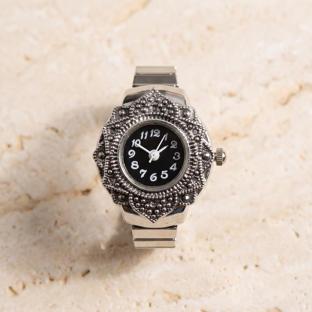 TIME — bague montre cadran noir, finition argentée, sur travertin crème