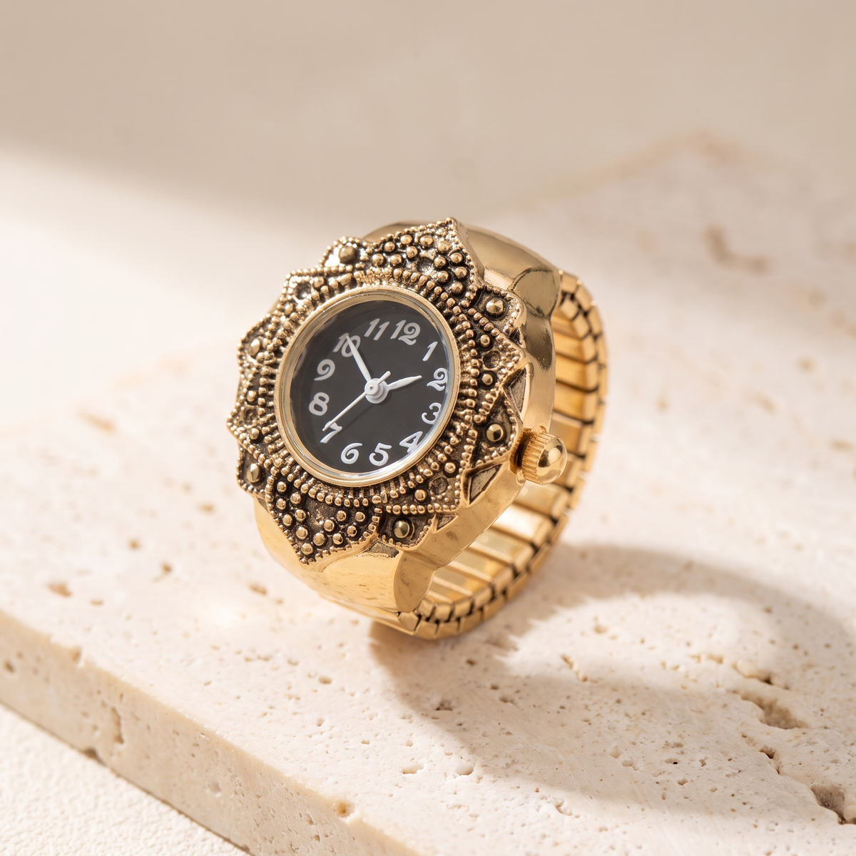 TIME — bague montre cadran noir, finition dorée, sur travertin crème